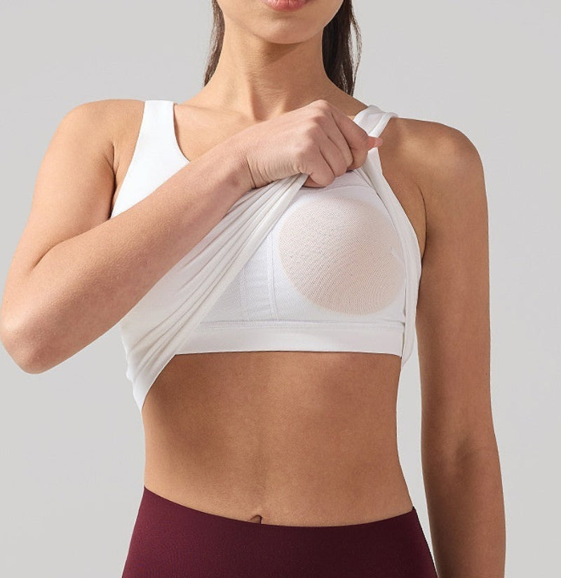 Woman wearing a white sports bra and maroon leggings against a light gray background