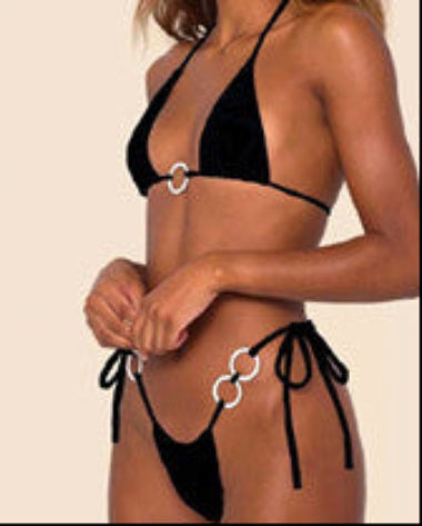 Woman wearing a colorful bikini with chain details on a beach.