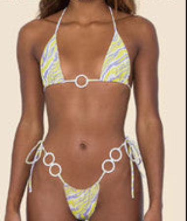 Woman wearing a colorful bikini with chain details on a beach.
