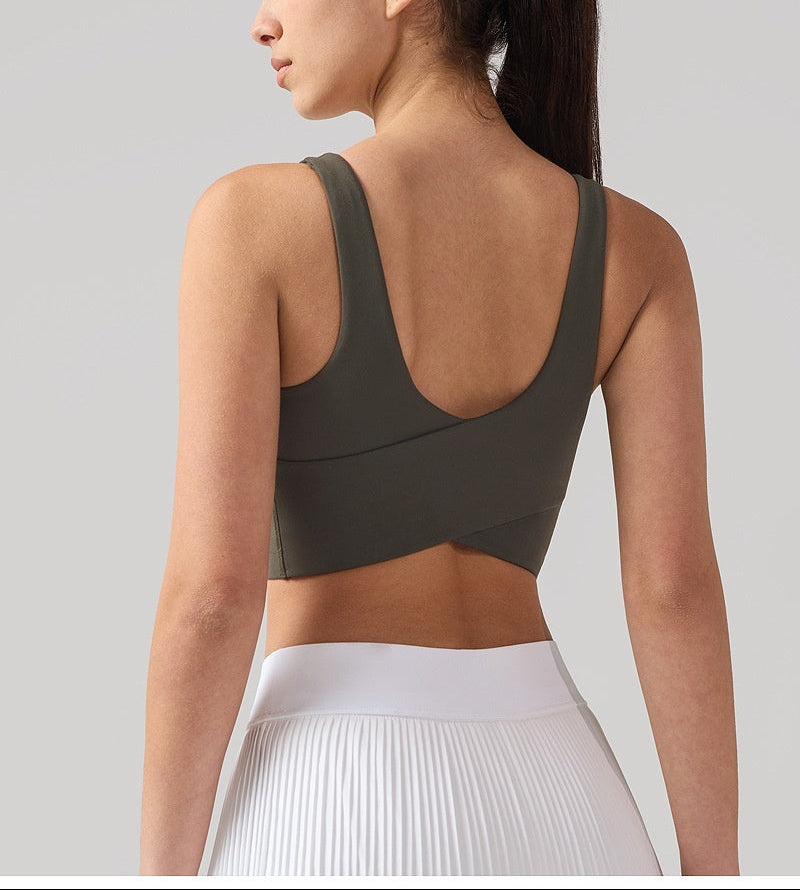 Woman wearing a green sports bra and white pants on a light gray background