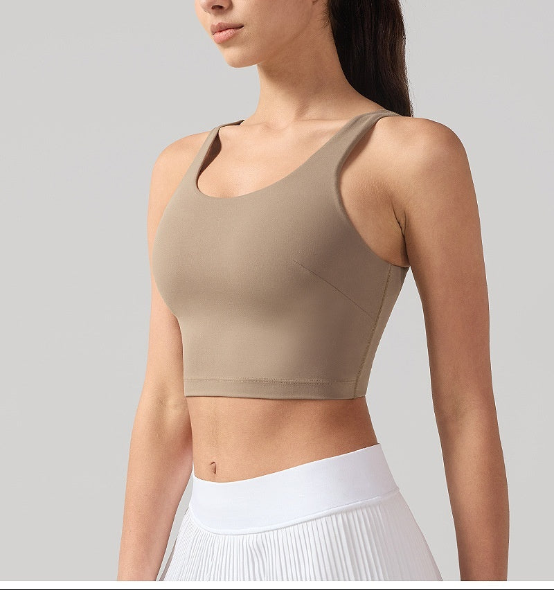 Woman wearing a beige sports bra and white pants on a gray background